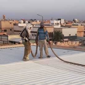عمال يقومون بعزل سطح هنجر